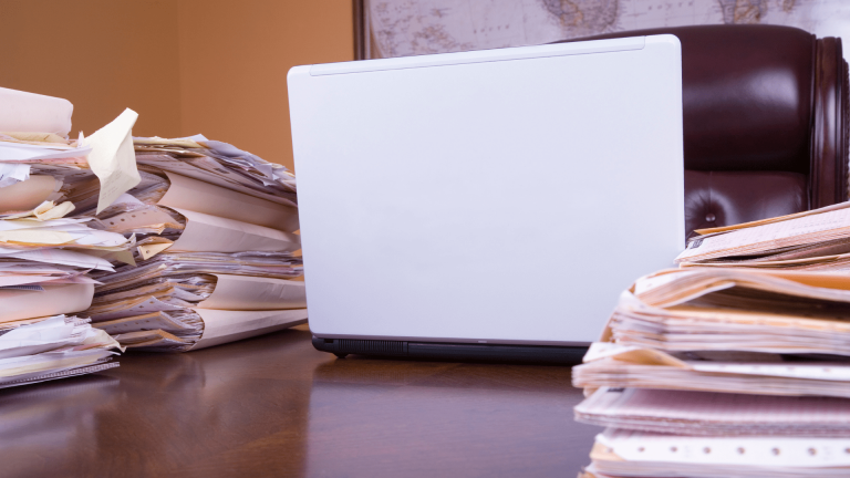 laptop surrounded by papers for shredding